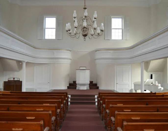 Bright traditional church sanctuary with white walls and wood pews